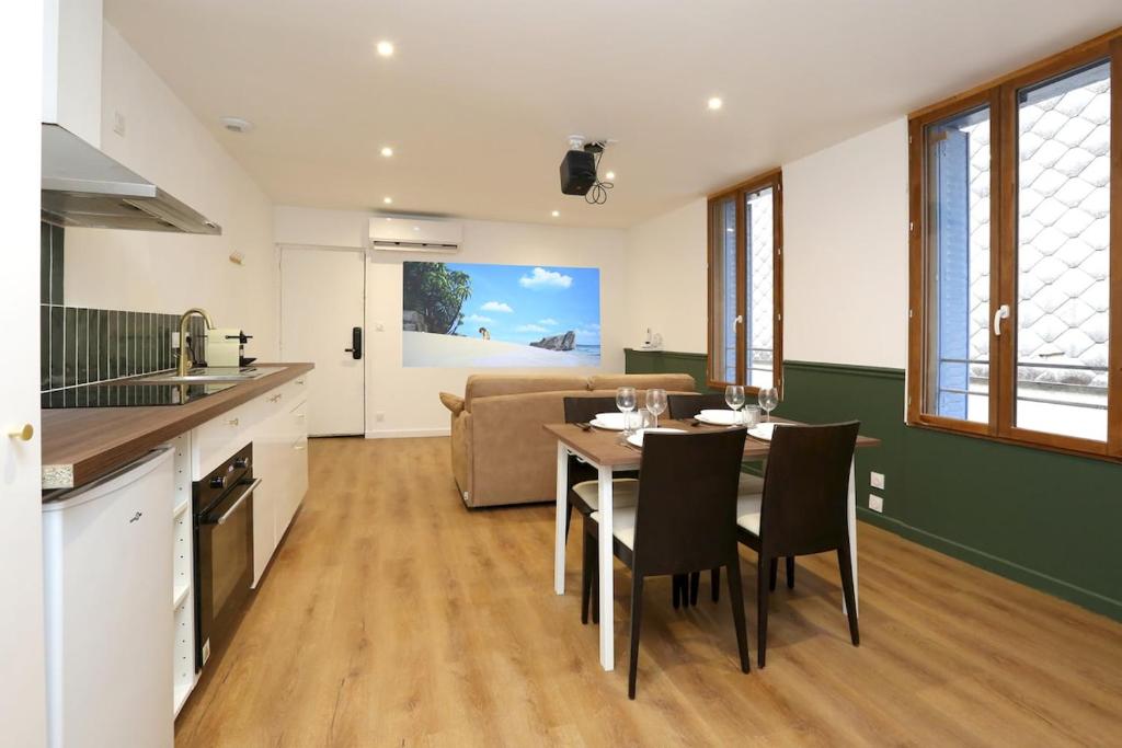 a kitchen and living room with a table and chairs at Superbe appartement avec écran géant in Tarbes