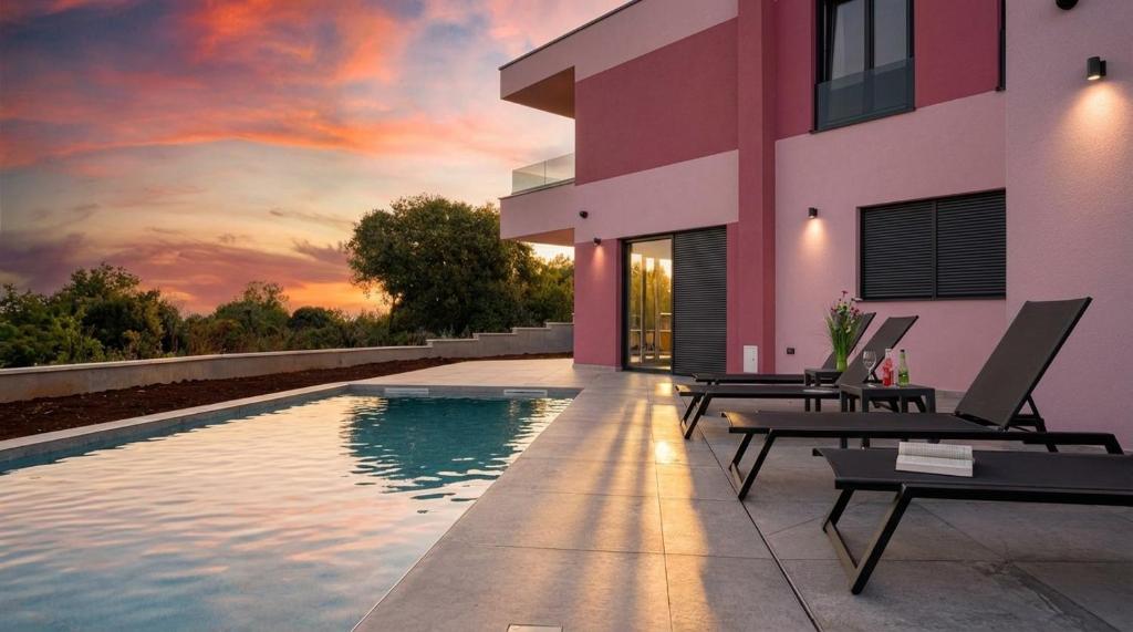 a house with a swimming pool with a sunset at Relaxing Villa Giardin in Premantura