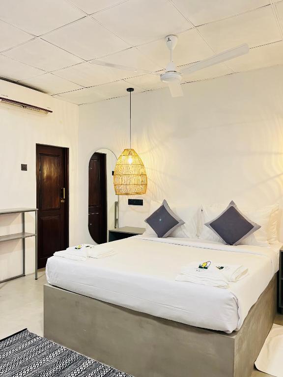a bedroom with a large white bed with a chandelier at La Manga Mirissa in Mirissa