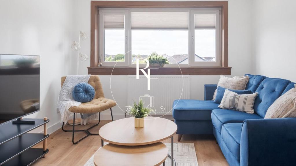 a living room with a blue couch and a table at The Den at Braehead in Cruden Bay
