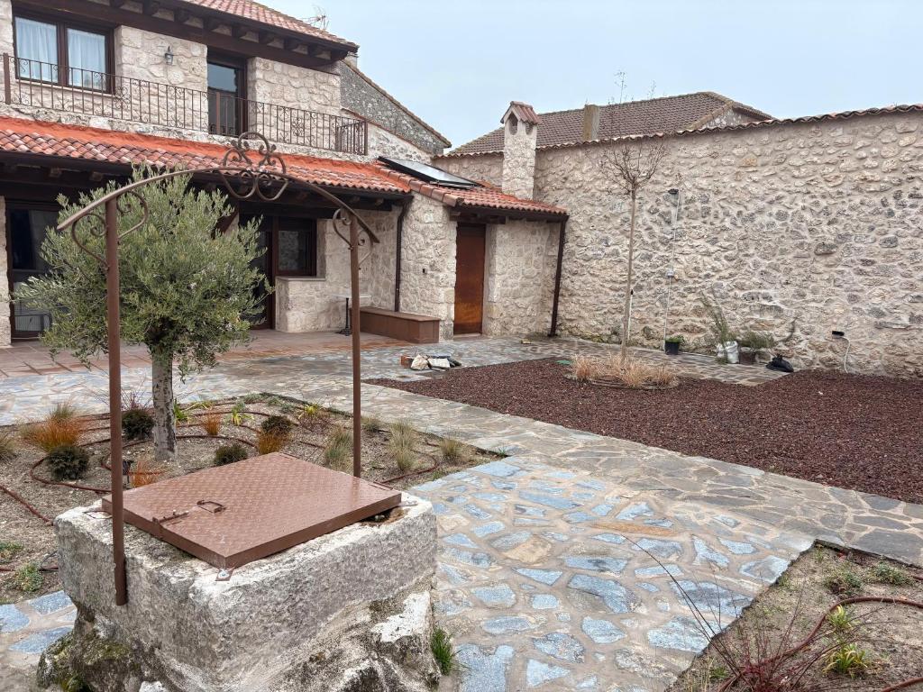 a stone building with a stone courtyard with a bench at El Jardín de los Olivos in Fuentesaúco de Fuentidueña
