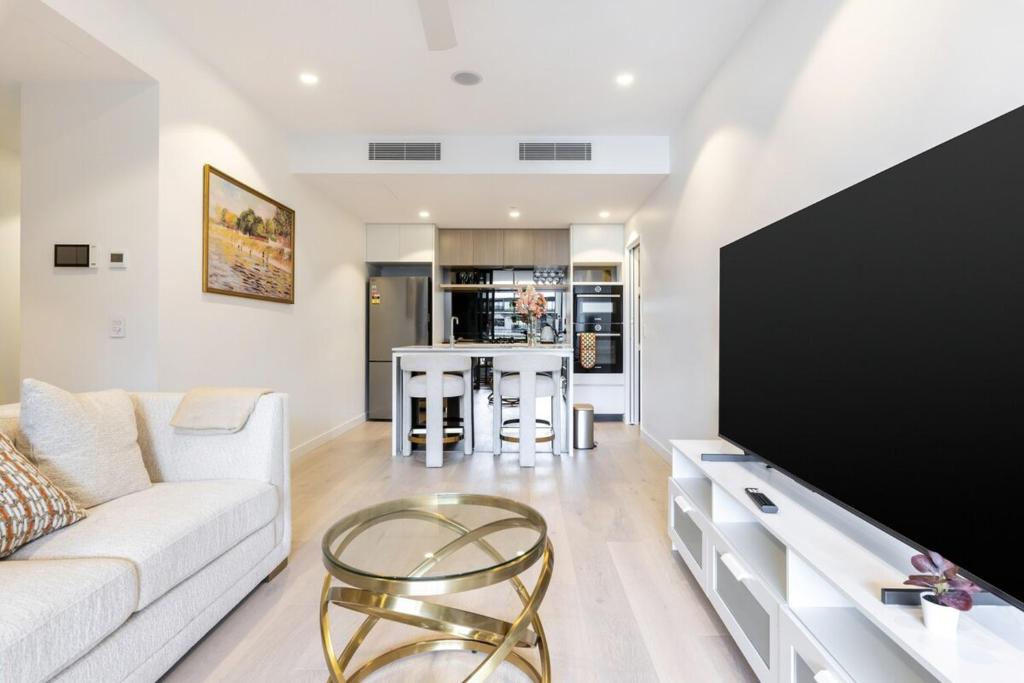 a living room with a couch and a large tv at Gorgeous 3BR Apartment with Study overlooking BNE River in Brisbane
