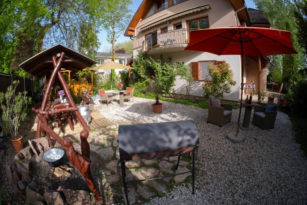a house with a patio with a red umbrella at Vicze Apartmanház in Siófok