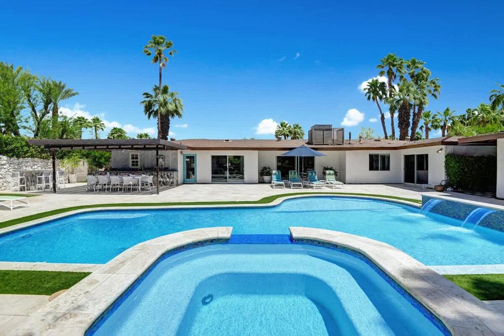 a pool in front of a house with palm trees at Palm 57 - Alice Lodging in Palm Springs