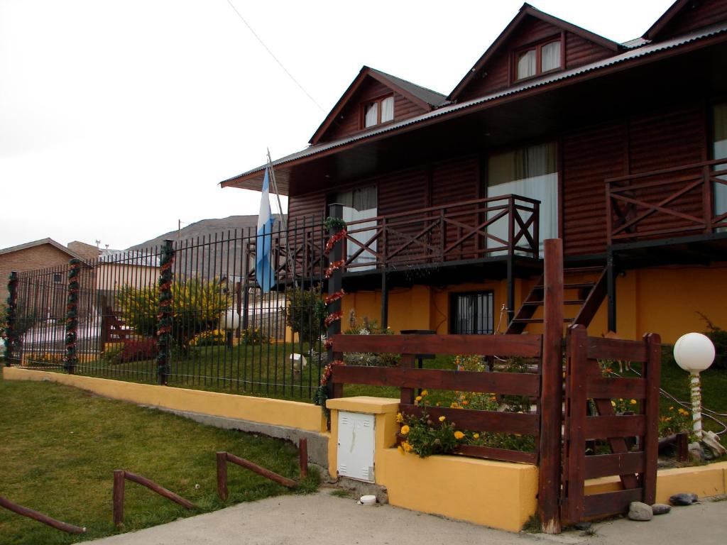 a house with a fence next to a yard at Cabañas Marias del Sur in El Calafate