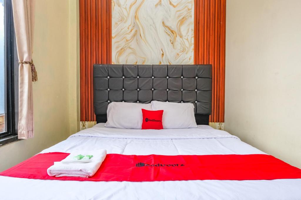 a bed with two towels and a red pillow on it at RedDoorz at Dieng 0KM in Diyeng