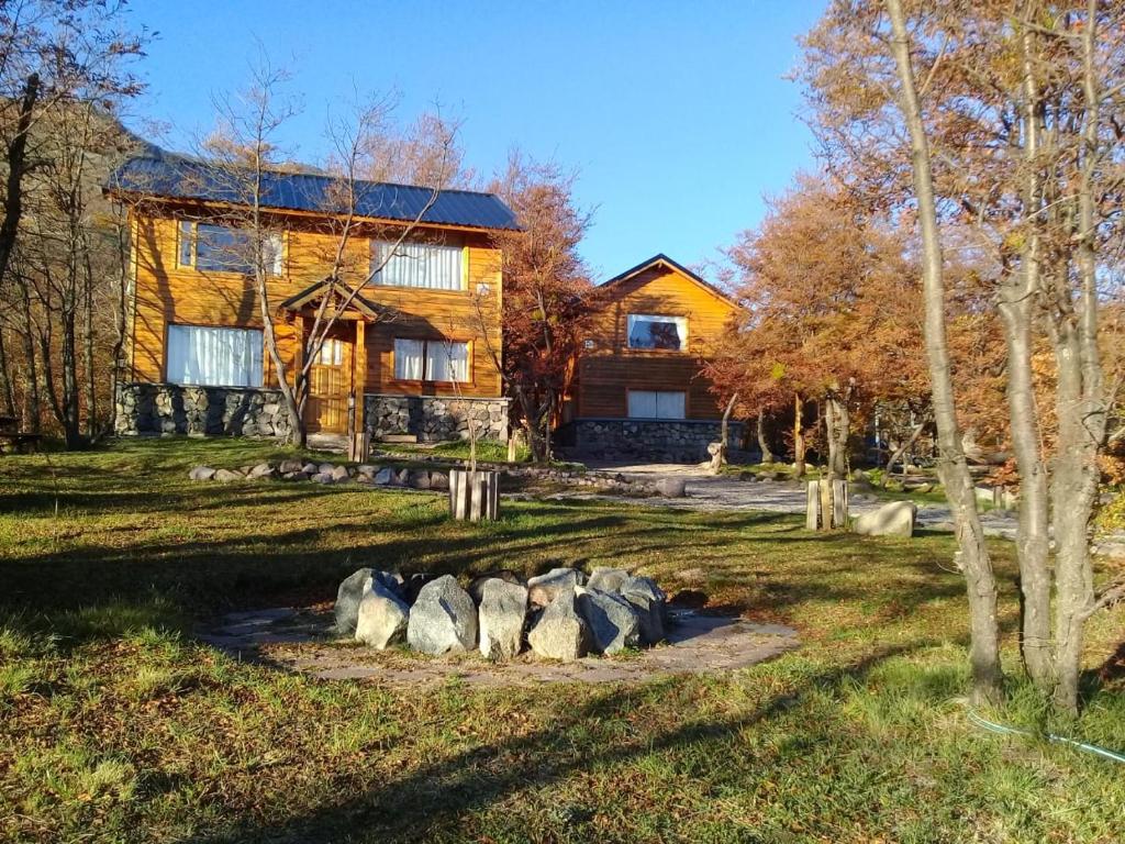 a log home with rocks in front of it at Rincon de Ñires cabaña 4 in San Martín de los Andes