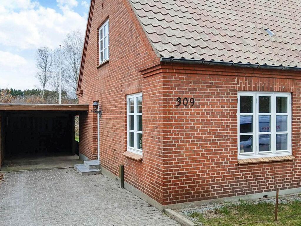 a red brick building with a garage and a door at Nature Escape Forest & Lake Access in Viborg