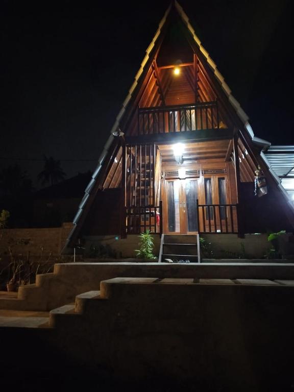 a wooden house with a light at night at Umah Pororo in Karangasem