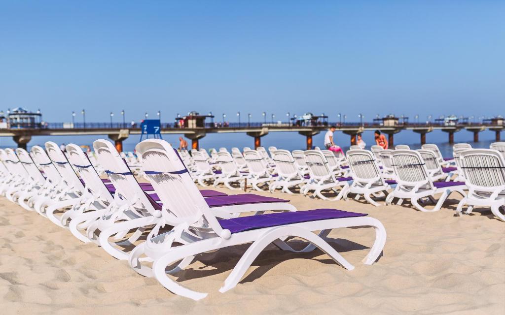 a row of lawn chairs on the beach at Hotel Aurora Family & SPA in Międzyzdroje