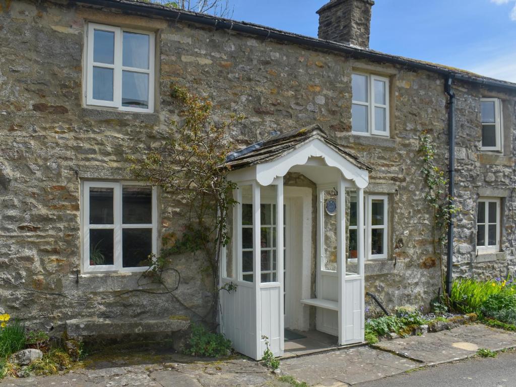 an old stone house with a white door at Horseshoe Cottage in Starbotton
