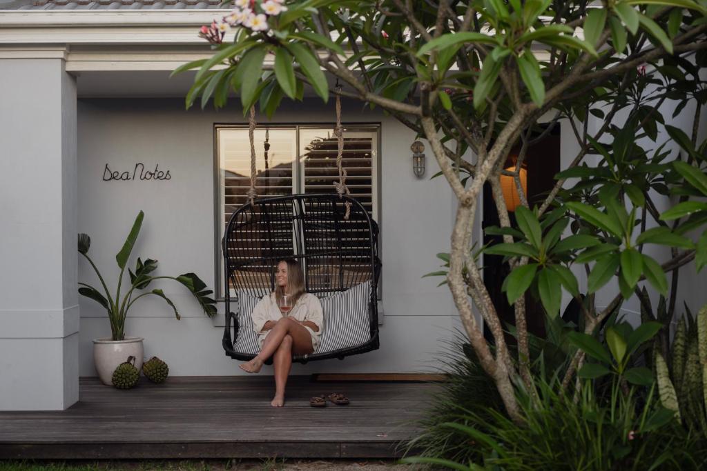 a woman sitting on a porch in a bird cage at Sea Notes Yamba in Yamba