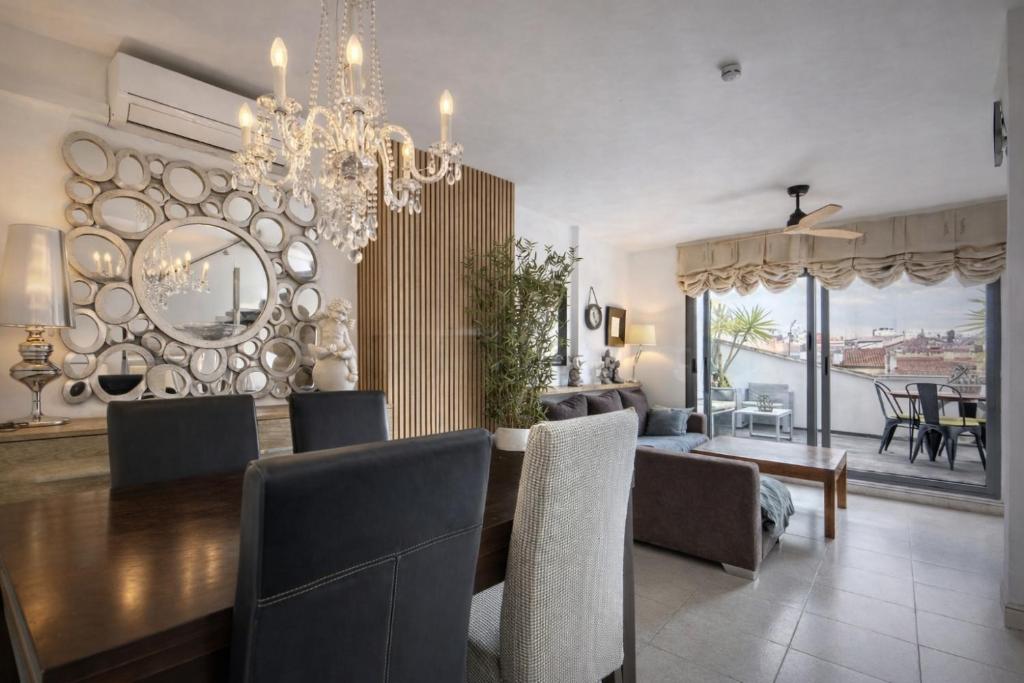 a dining room with a table and a chandelier at Attic Center Sitges in Sitges
