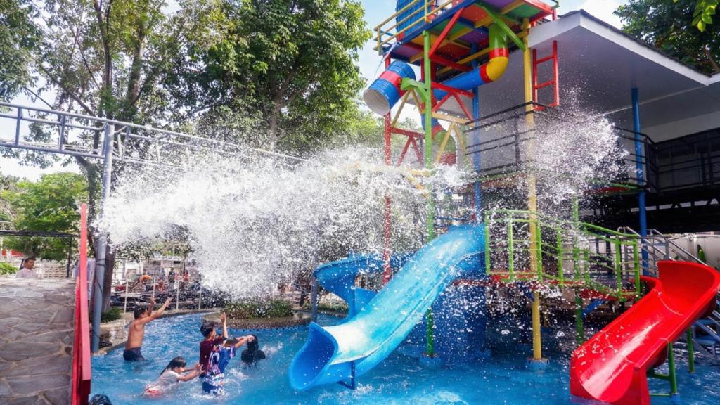 a group of children playing on a water slide at a water park at Grand Rohan Jogja in Yogyakarta