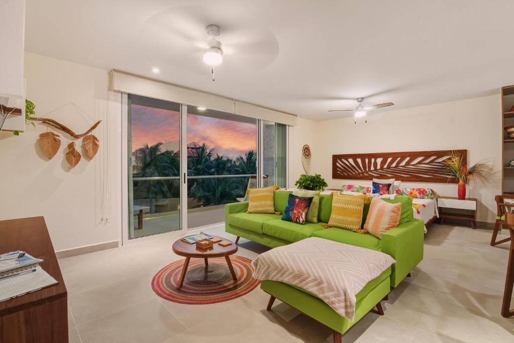 a living room with a green couch and a table at Akumal Cielo Seven Ocean View Pools Beach Access in Akumal