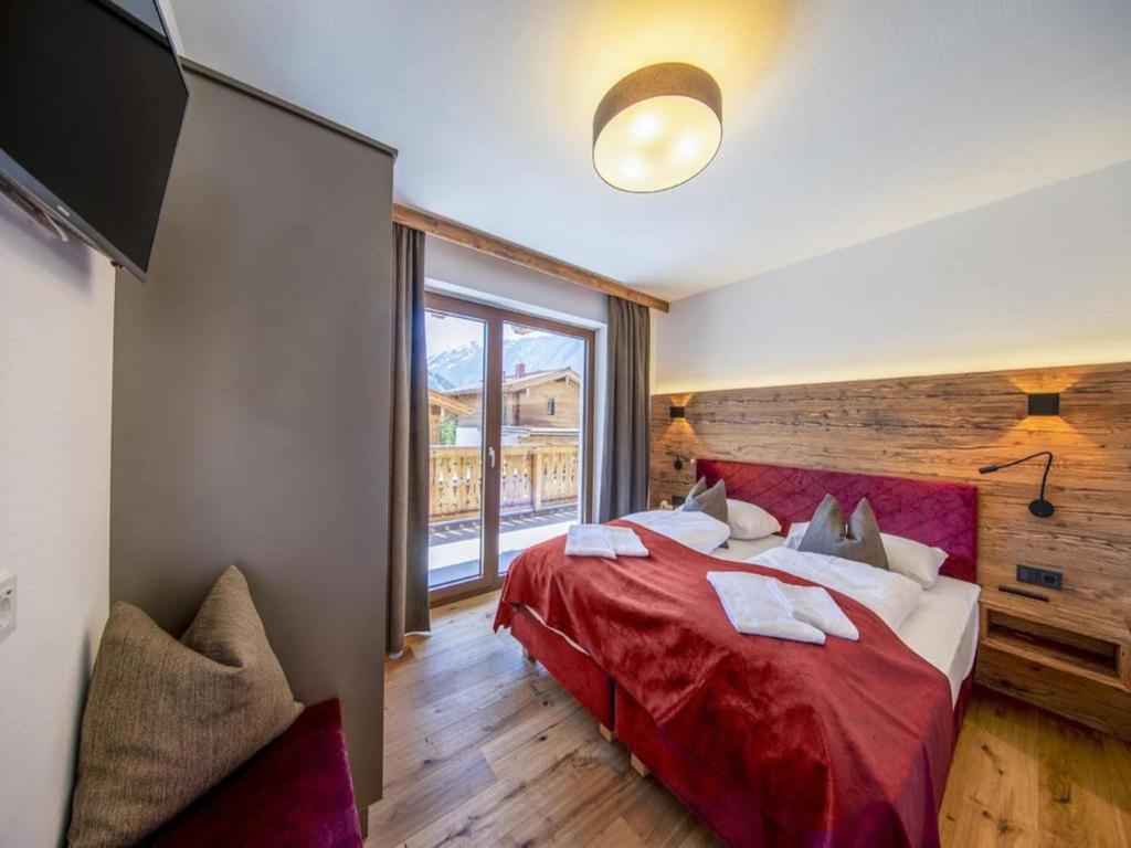 a bedroom with a red bed and a large window at Chalet with sauna, Neukirchen in Neukirchen am Großvenediger