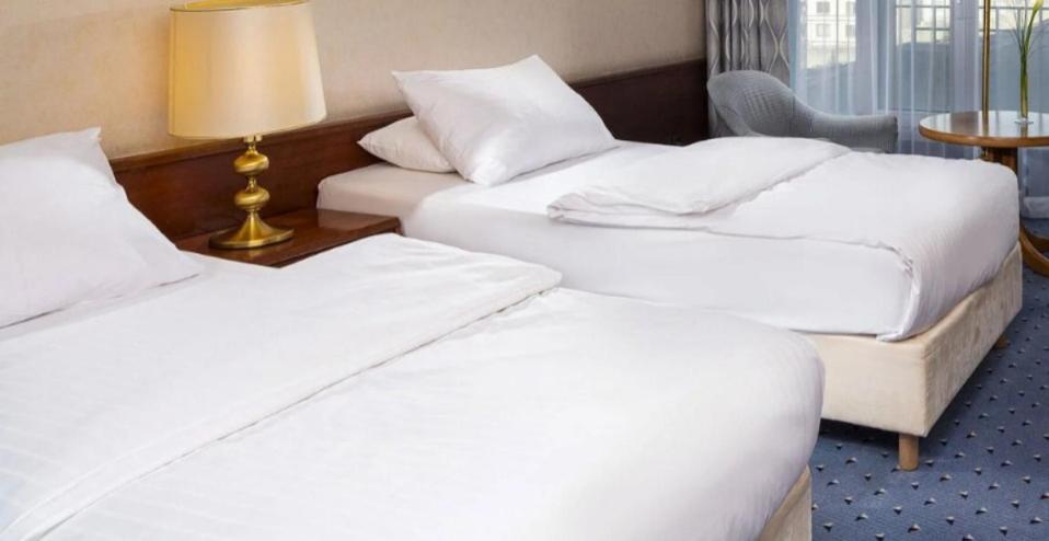 two beds in a hotel room with white sheets at Hotel La Posada de los Volcanes - ALTARA in Arequipa