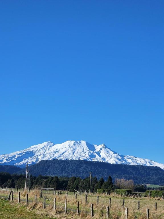 a snow covered mountain in the distance with a fence at Ruapehu Farm Chalet in Ohakune