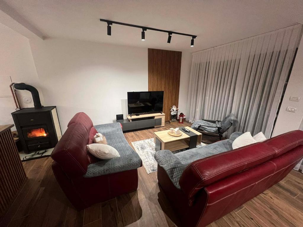 a living room with a red leather couch and a fireplace at Vila Davidoski in Mavrovo