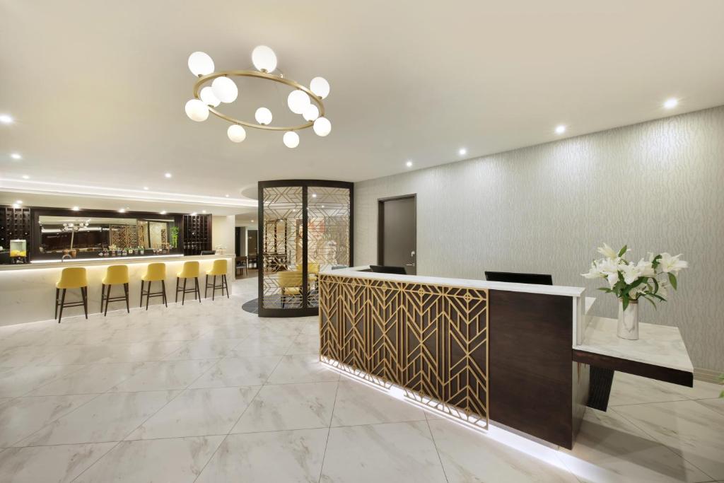 a lobby with a bar with yellow chairs and a chandelier at Swiss-Belhotel Napier in Napier