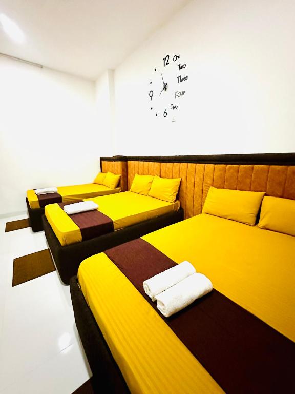three beds in a room with a clock on the wall at Dreamy Homestay in Anuradhapura