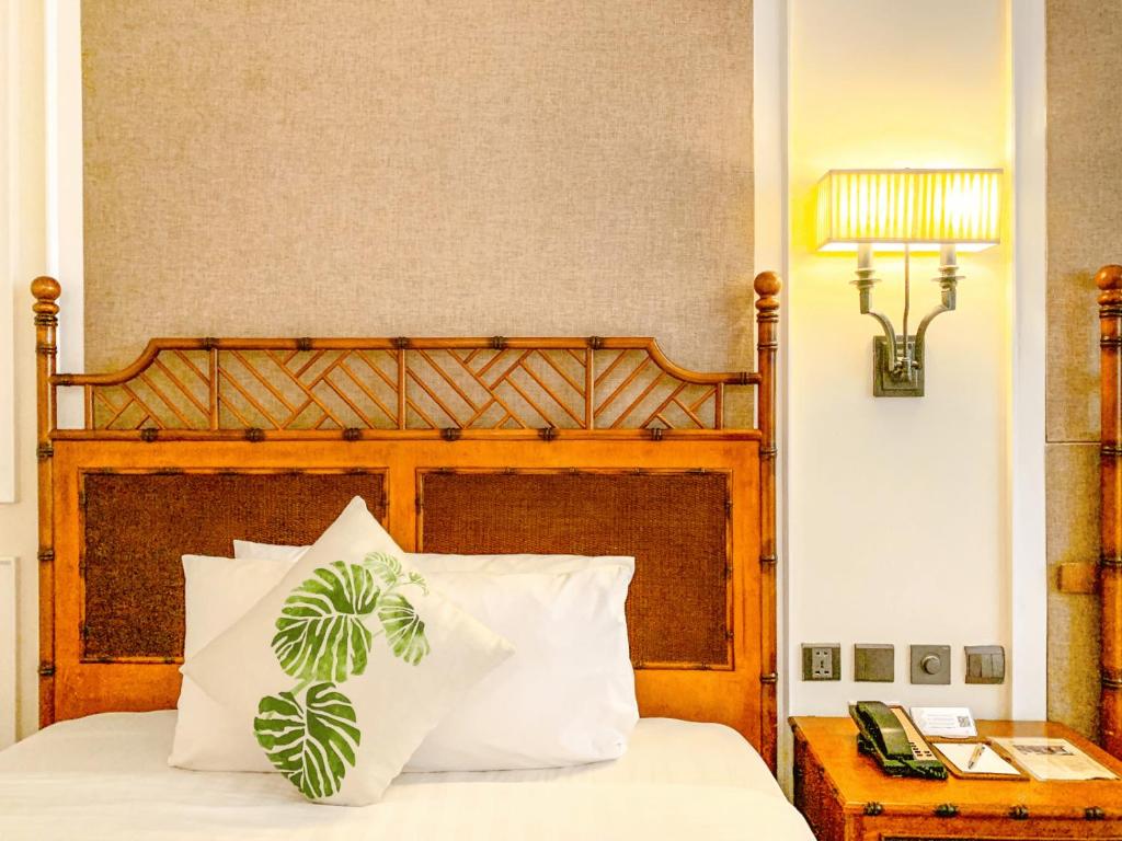 a bed with a wooden headboard with two white pillows at Feliz Hotel Boracay in Boracay