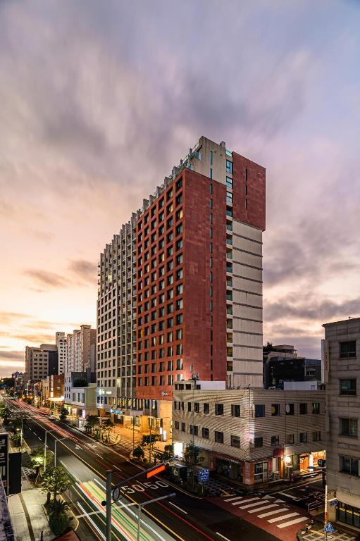 a tall red building in the middle of a city at Hotel Air City Jeju in Jeju