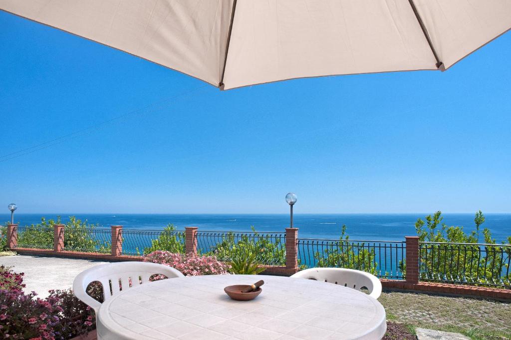 tavolo e sedie con ombrellone e oceano di Le Terrazze Appartamenti Vacanze a Sanremo