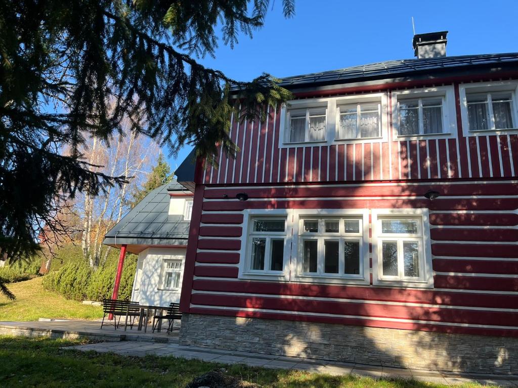 a red house with a bench in front of it at Rychtrova bouda Benecko in Benecko