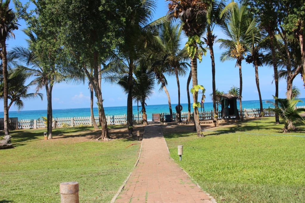 a brick path leading to a beach with palm trees at Royal Wave, Beachfront, Nilaveli in Trincomalee