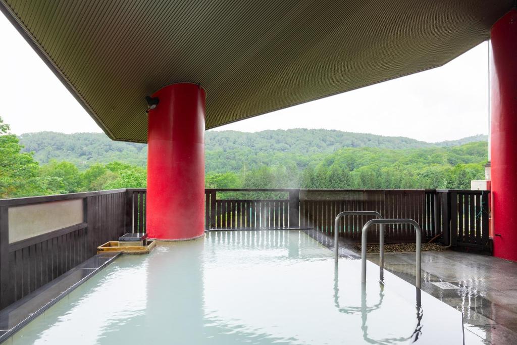 une mare d'eau avec un poteau rouge au milieu dans l'établissement Hotel Kanronomori, à Niseko