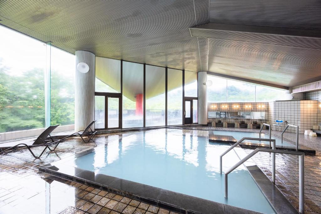 une grande piscine dans un bâtiment avec des fenêtres dans l'établissement Hotel Kanronomori, à Niseko