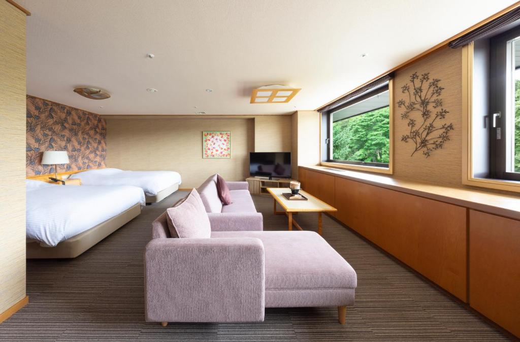 une chambre d'hôtel avec deux lits et un canapé dans l'établissement Hotel Kanronomori, à Niseko