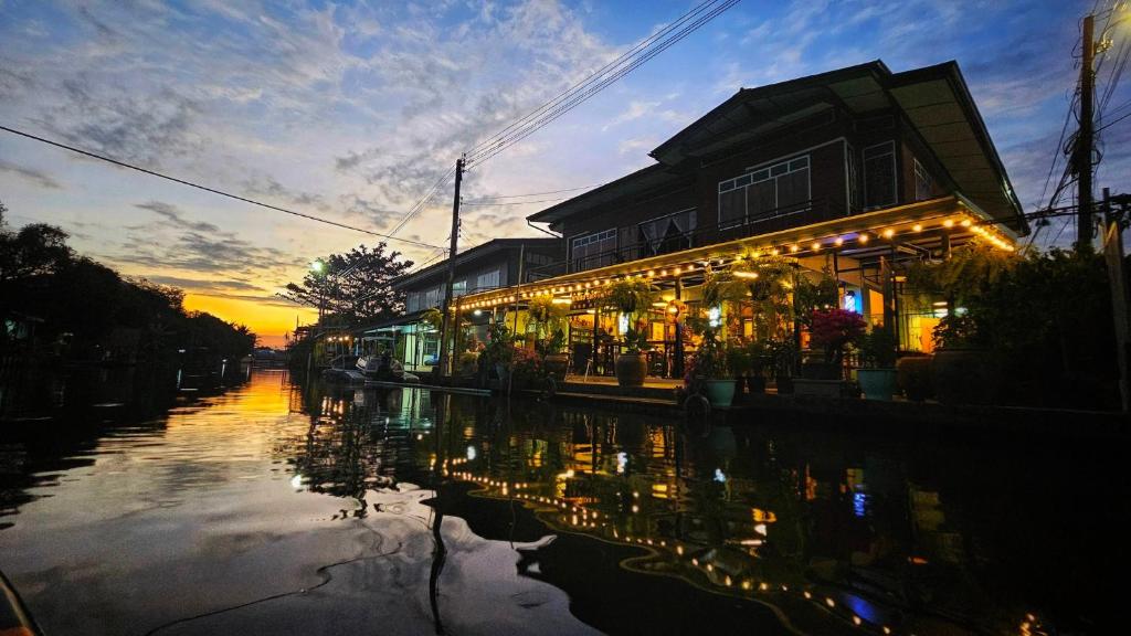 a building with lights on a canal at sunset at นำสมัย สุขใจ สนามชัย in Bangkok