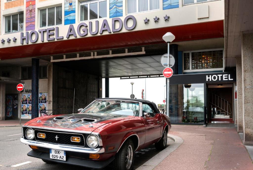 a red car parked in front of a hotel la palapa at Hotel Aguado in Dieppe