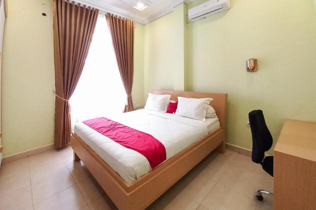 a bedroom with a bed and a desk and a window at RedDoorz Syariah at UIN Suska GuestHouse in Pekanbaru