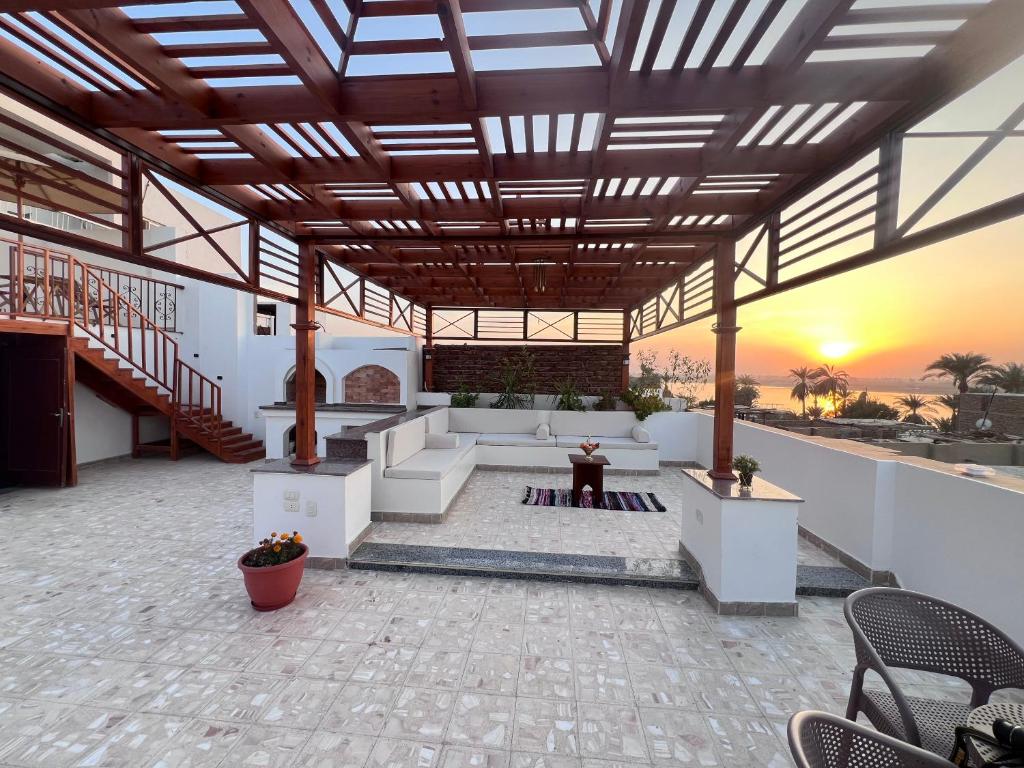 a patio with a couch and a sunset in the background at Spacious Luxury Nile-View Apartment on Upper Floor with Rooftop, Jacuzzi & BBQ ,Steps from Hilton Hotel in Luxor