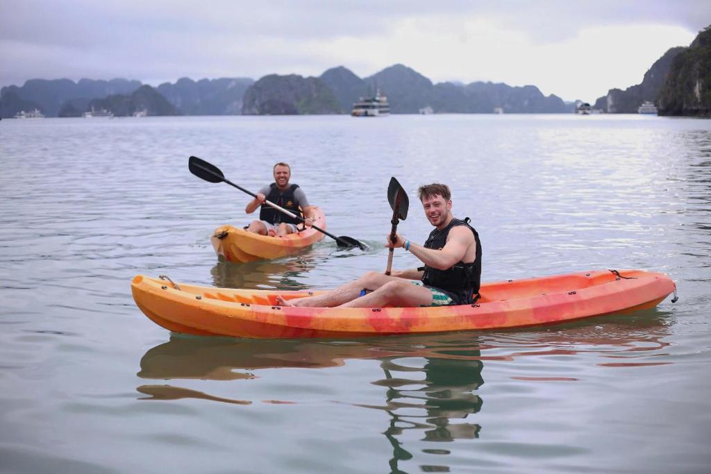 two men in kayaks on a body of water at Manh Vuong Buotique Hotel in Cat Ba