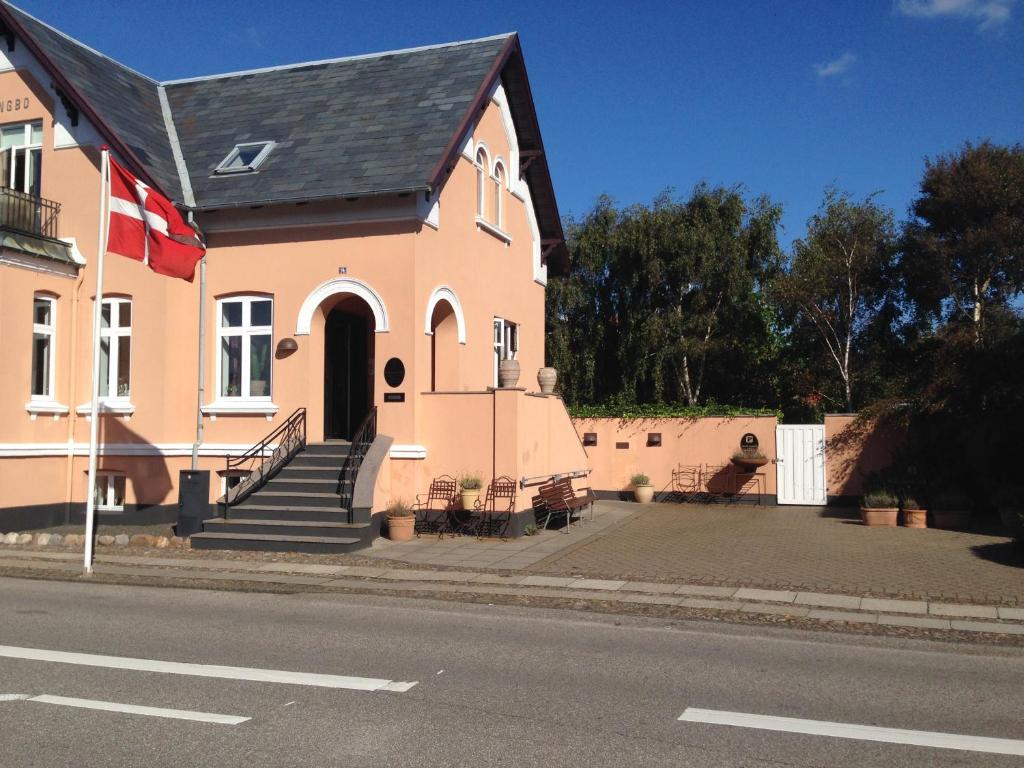 uma casa cor-de-rosa com um telhado preto numa rua em Engbo em Ringkøbing