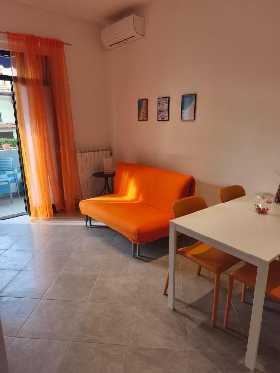 a living room with an orange couch and a table at Il Chicco di Arianna in Torre del Lago Puccini