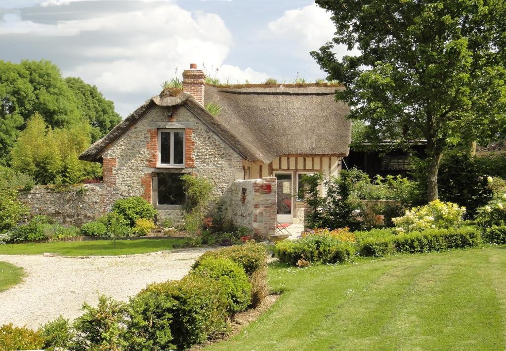 una antigua casa de campo de piedra con un jardín frente a ella en La Petite Chaumière, en Gonneville-sur-Honfleur