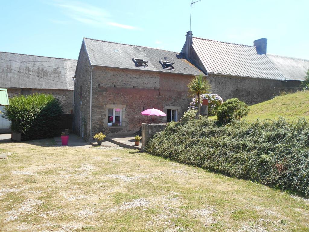 a house with a pink umbrella in front of it at Gite de la Huberderie in Quettehou