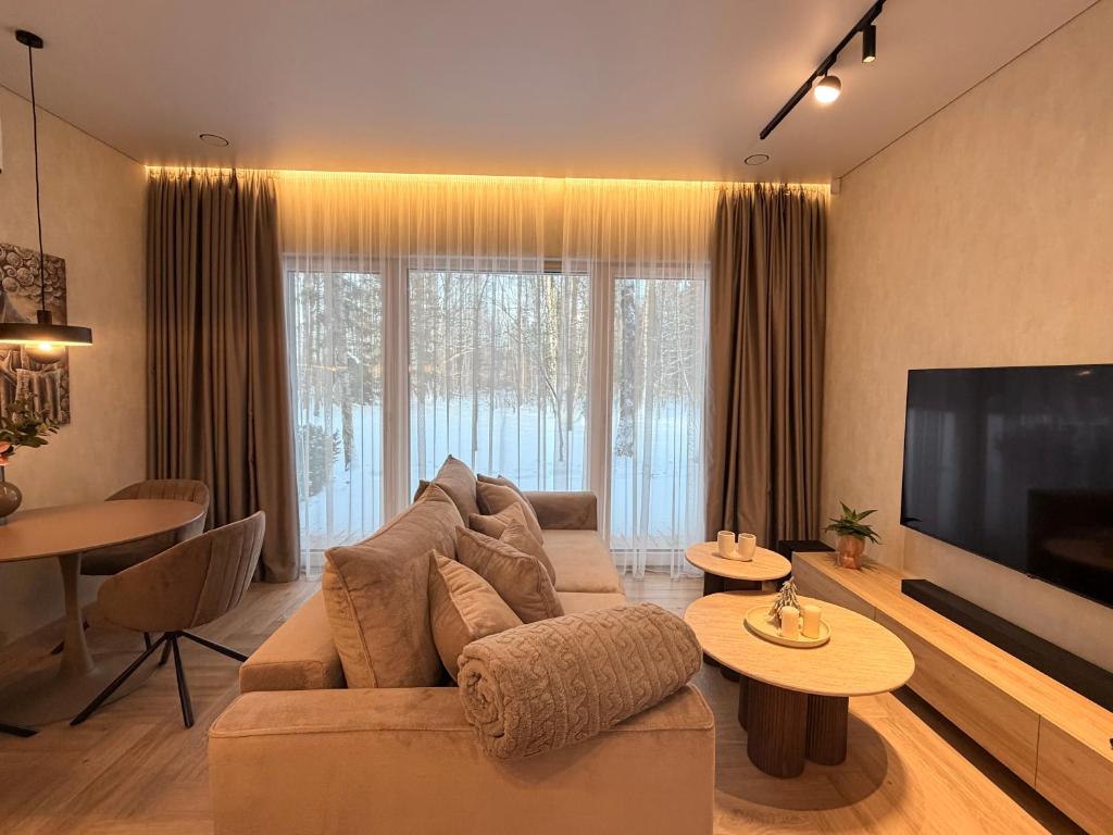ein Wohnzimmer mit Sofa und Flachbildfernseher in der Unterkunft Pine Forest Residence in Melnragė