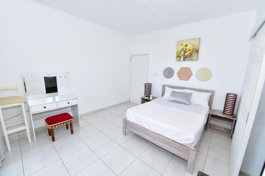 a white bedroom with a bed and a desk at Hyacinth Golf& Sea in Grand-Baie