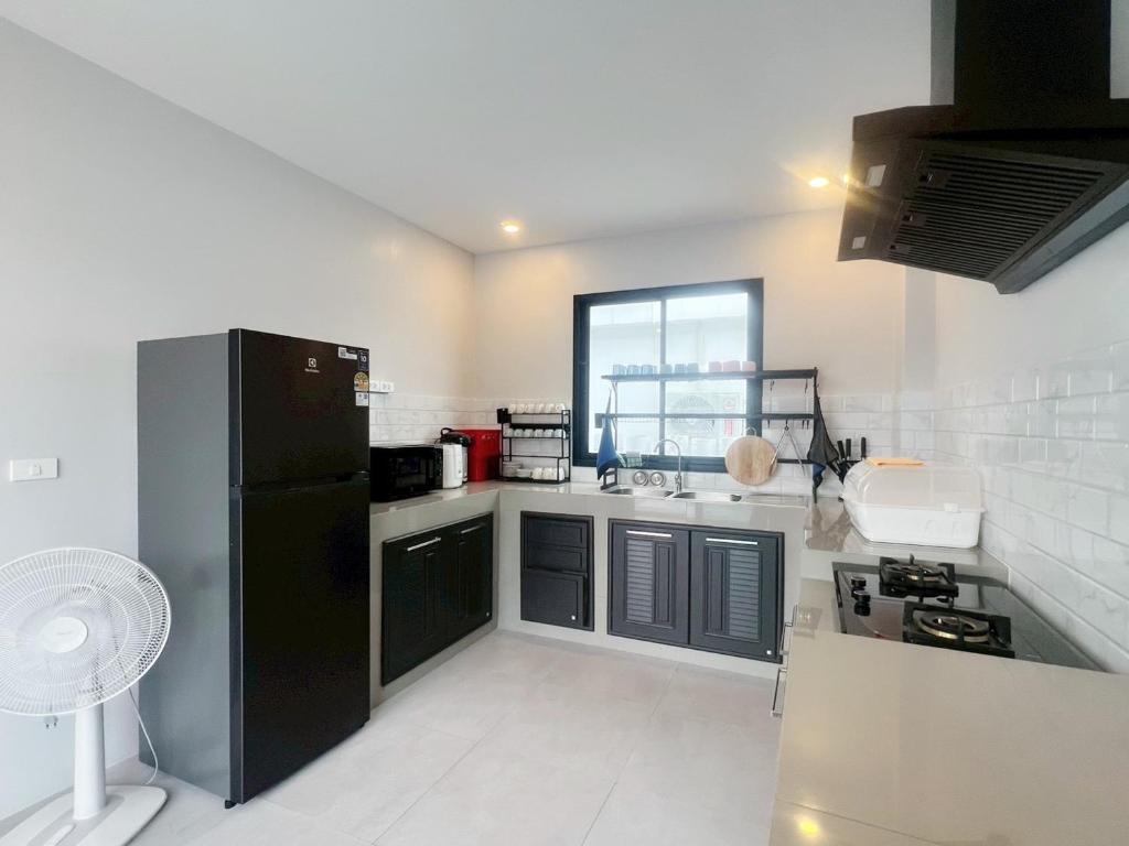 a kitchen with a black refrigerator and a window at Pool villa Cream Darin in Ban Hua Phrong
