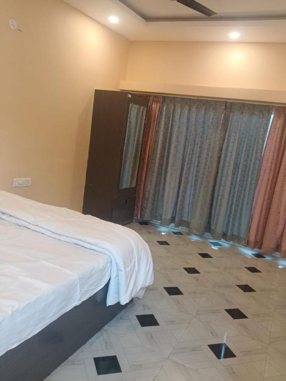 a bedroom with a bed and a window with curtains at Riyank Farms in Patna