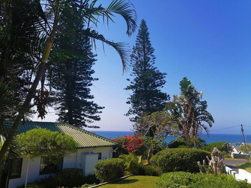 a house with trees and the ocean in the background at BillsBest Greengates Cottages in Port Edward