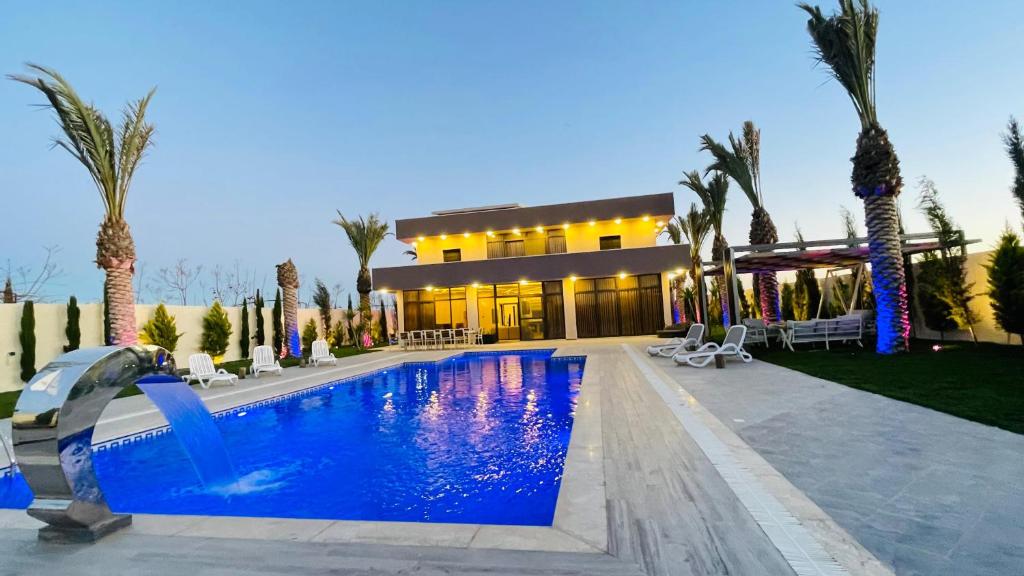 a swimming pool in front of a house with palm trees at Villa W2 in Amman