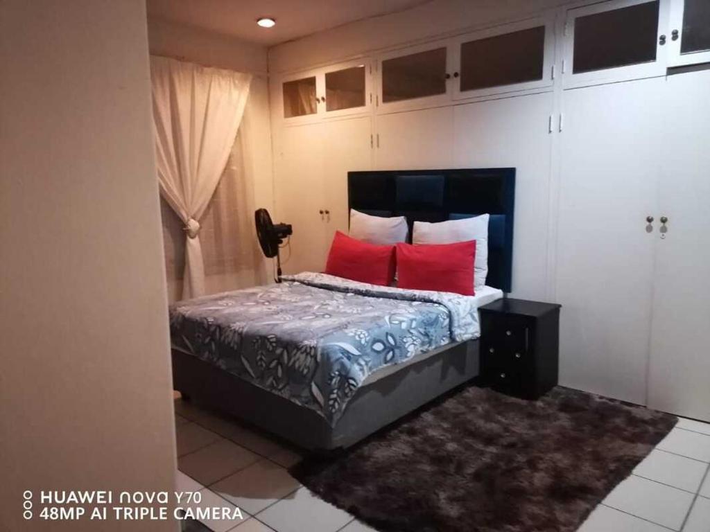 a bedroom with a bed with red pillows at Matte Guest House in Potchefstroom
