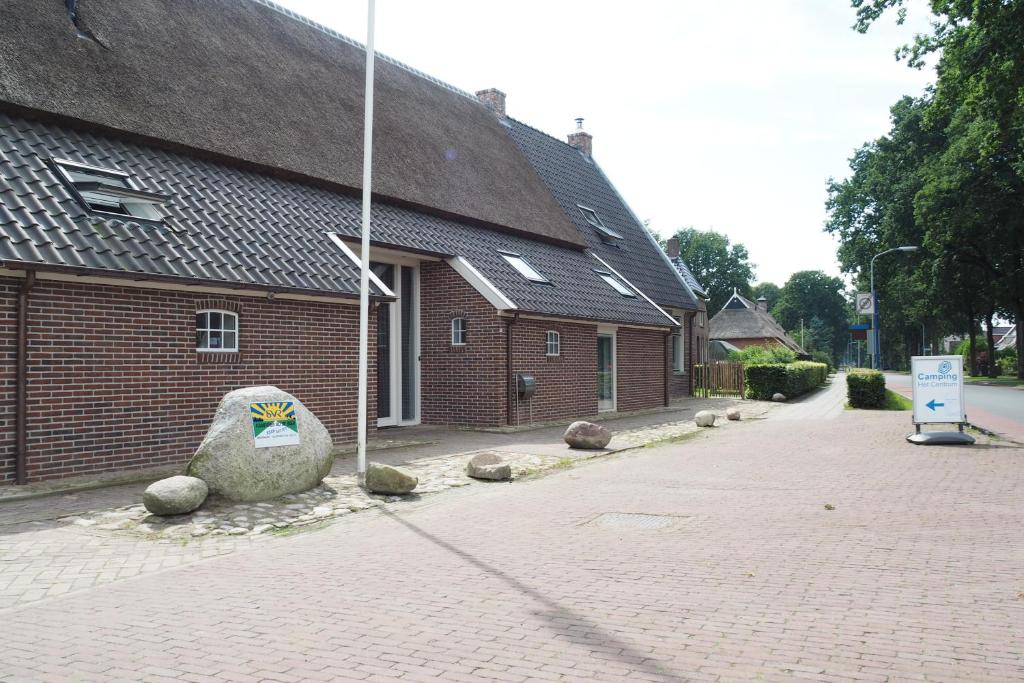 a brick building with a large rock next to a street at Het Centrum in Norg
